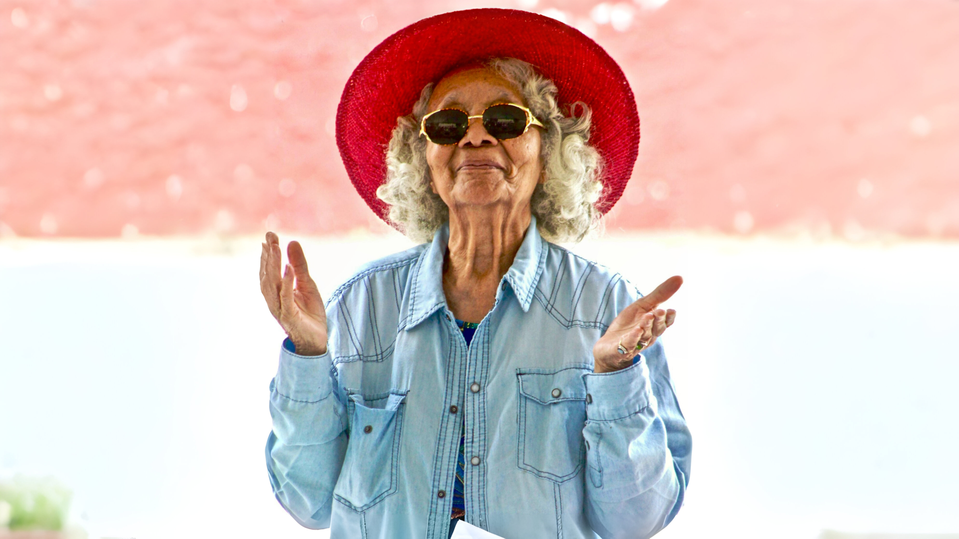 Une femme âgée portant des lunettes de soleil et un chapeau rouge - Domicil’à vie