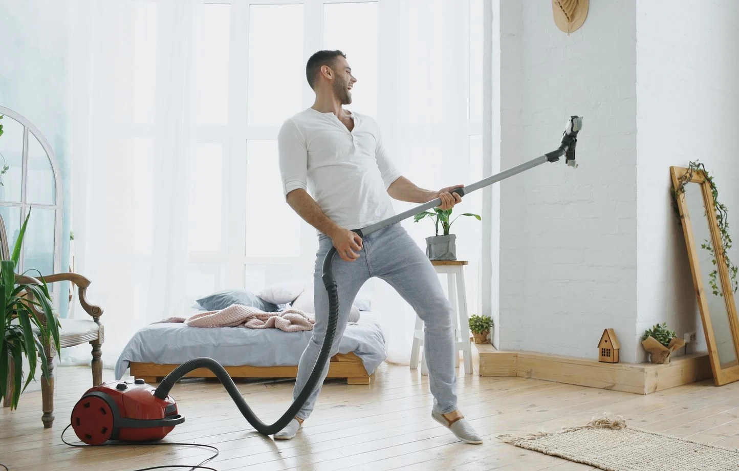 Un homme faisant le ménage se servant de son aspirateur comme d'une guitare  - Domicil'à vie